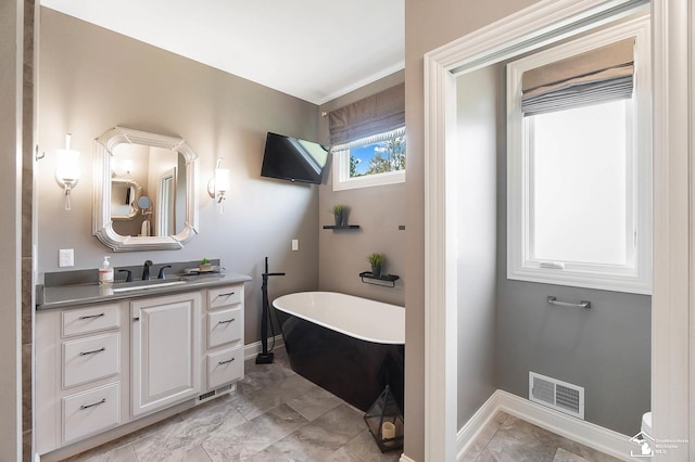 full bath with visible vents, vanity, toilet, baseboards, and a soaking tub