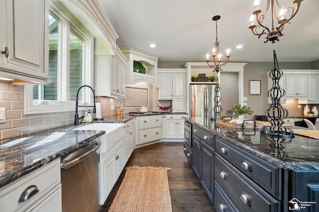 kitchen featuring pendant lighting, stainless steel appliances, a notable chandelier, and white cabinetry