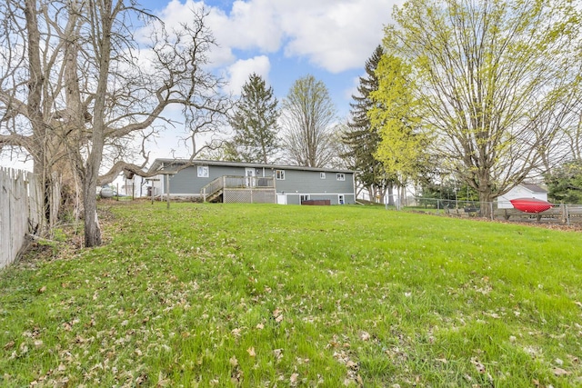 view of yard with a fenced backyard, a wooden deck, and stairway
