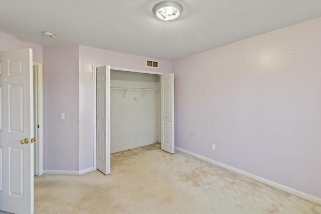 unfurnished bedroom with light colored carpet, baseboards, visible vents, and a closet