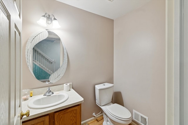 half bath with vanity, toilet, and visible vents