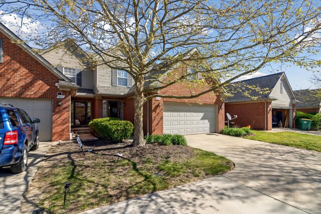 traditional-style home featuring brick siding, an attached garage, and driveway
