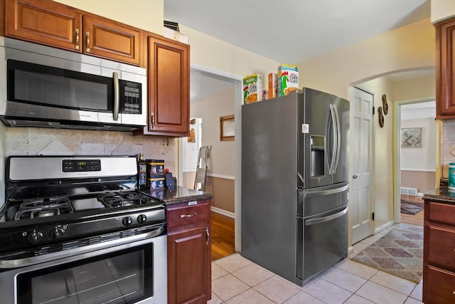 kitchen featuring visible vents, appliances with stainless steel finishes, tasteful backsplash, arched walkways, and light tile patterned floors