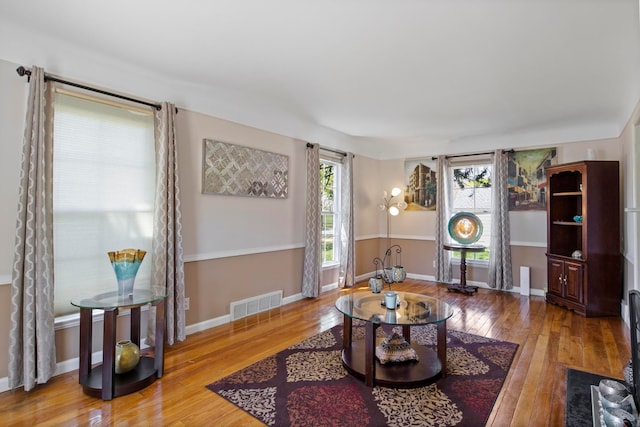 living area with visible vents, baseboards, and hardwood / wood-style flooring