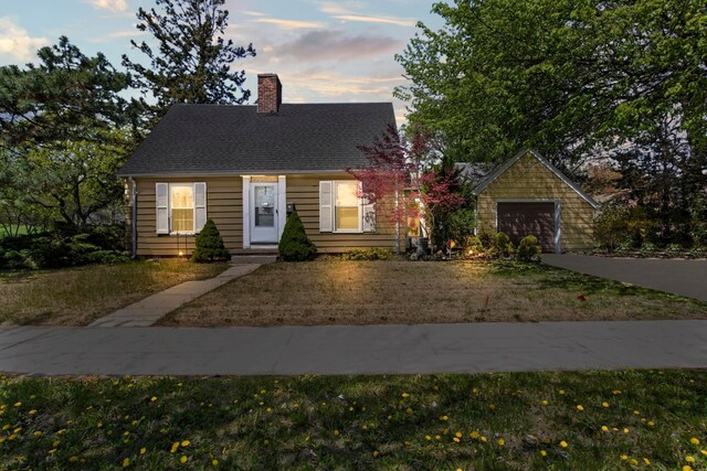 cape cod home featuring a shingled roof, a front lawn, and a chimney