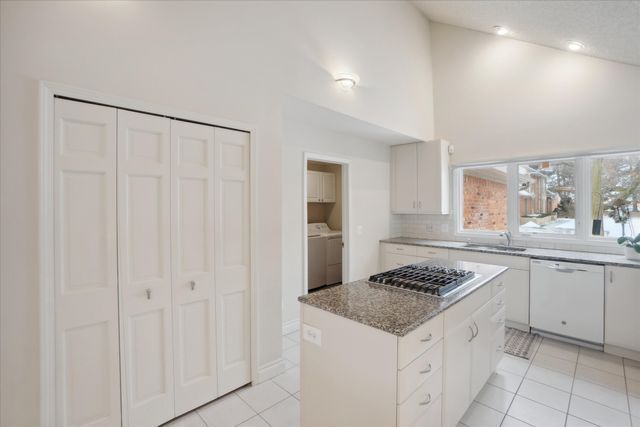kitchen with light tile patterned flooring, white dishwasher, a center island, a sink, and stainless steel gas stovetop