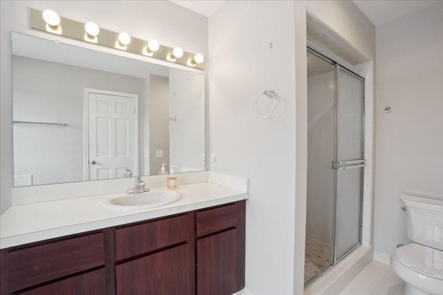 bathroom featuring toilet, tile patterned floors, a shower stall, and vanity