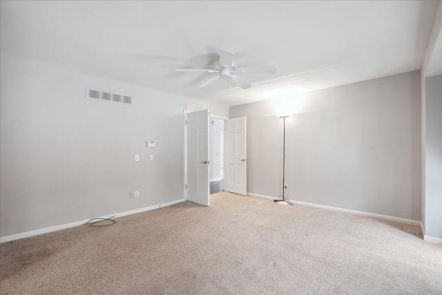 empty room with a ceiling fan, baseboards, visible vents, and light carpet