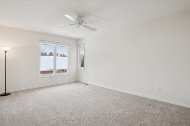 carpeted empty room with baseboards and ceiling fan