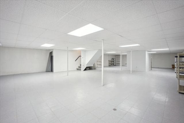 finished below grade area featuring stairs and a drop ceiling