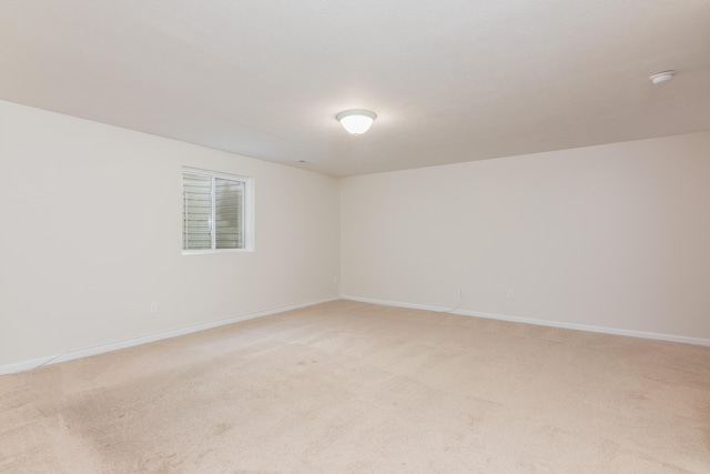empty room featuring baseboards and light colored carpet