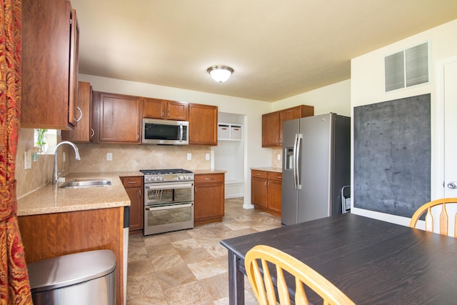 kitchen with visible vents, brown cabinetry, tasteful backsplash, a sink, and stainless steel appliances