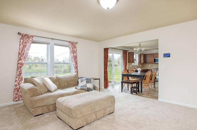 living area featuring baseboards, light carpet, and a notable chandelier