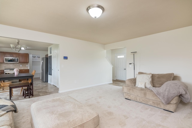 living area featuring light colored carpet, baseboards, and a notable chandelier