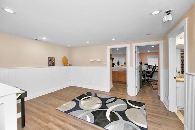 interior space with visible vents, light wood-type flooring, and a wainscoted wall