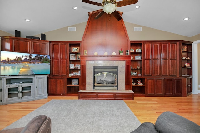 living area with ceiling fan, visible vents, a tile fireplace, and light wood-style floors