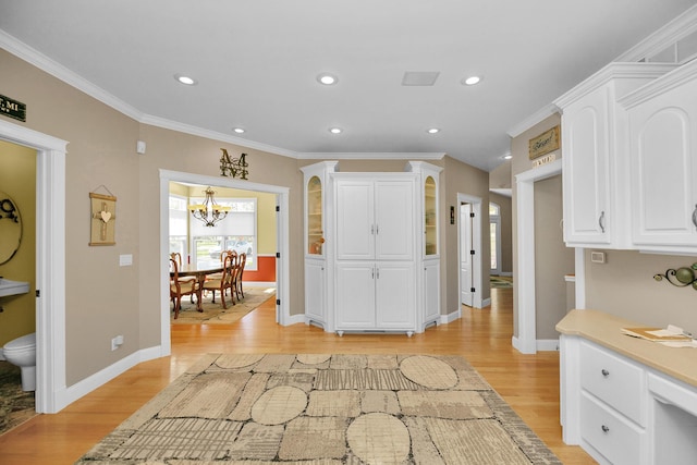 interior space featuring crown molding, baseboards, an inviting chandelier, and light wood-type flooring