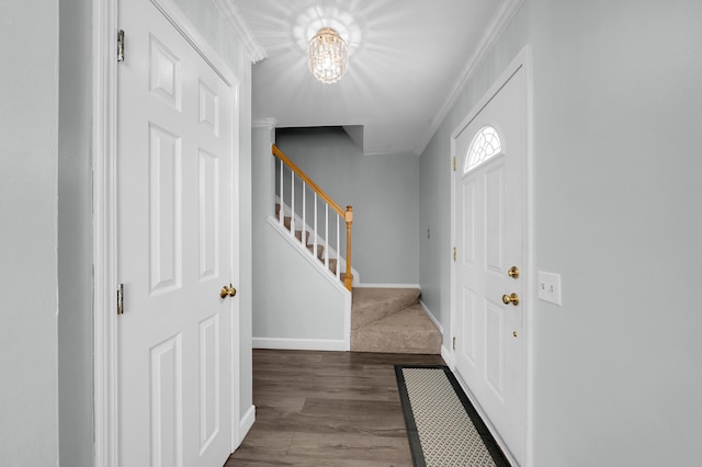 foyer entrance with crown molding, a notable chandelier, baseboards, wood finished floors, and stairway