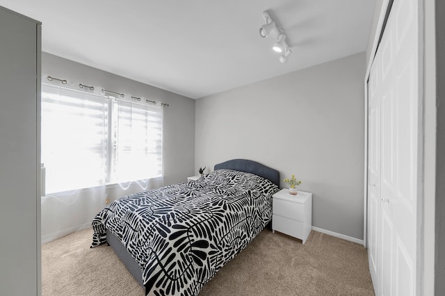 carpeted bedroom featuring baseboards and a closet