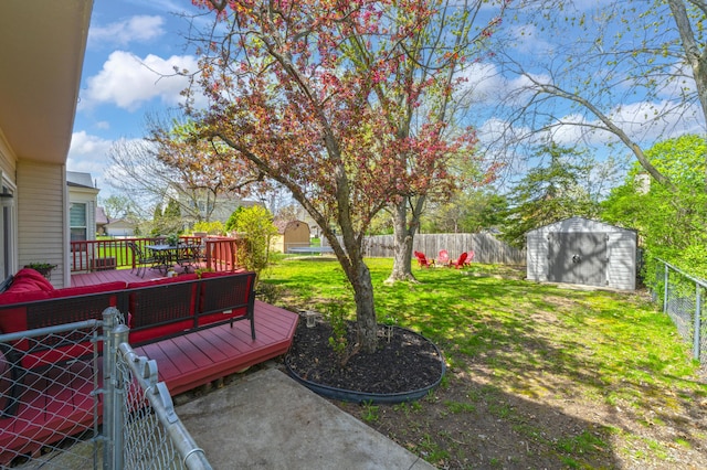 view of yard featuring a fenced backyard, a storage unit, a wooden deck, and an outbuilding