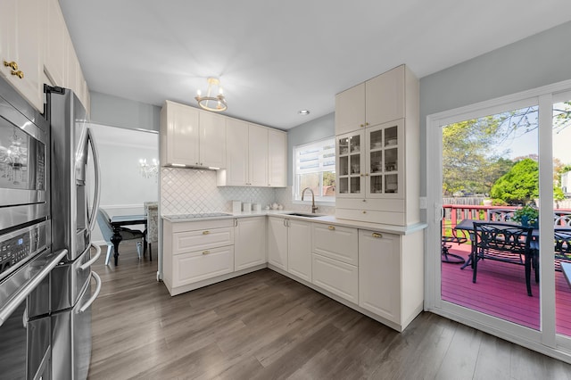 kitchen featuring decorative backsplash, light countertops, white cabinets, a sink, and appliances with stainless steel finishes
