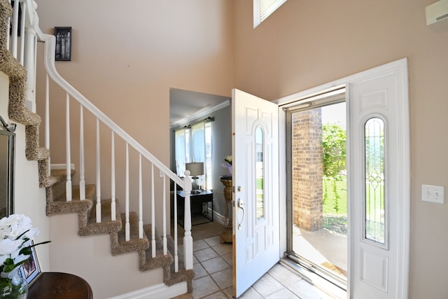 51466 Promenade Ln, New Baltimore, MI 48047 - entryway with light tile patterned floors, stairs, crown molding, and a towering ceiling