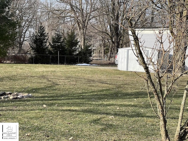 view of yard featuring fence, a storage unit, and an outbuilding