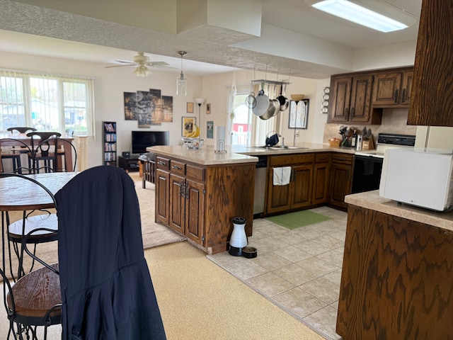 kitchen with electric range, ceiling fan, light countertops, a peninsula, and stainless steel dishwasher