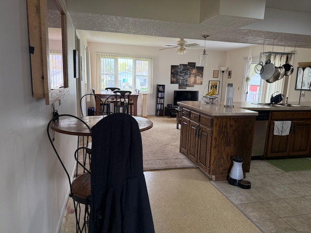 kitchen with ceiling fan, light colored carpet, a sink, baseboards, and open floor plan
