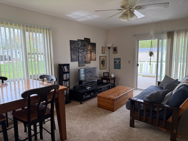 carpeted living area with a ceiling fan