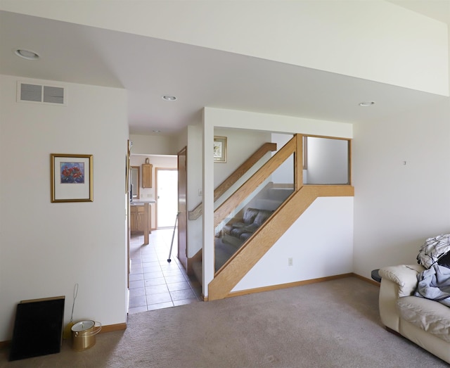 living area featuring carpet flooring, baseboards, visible vents, and stairway