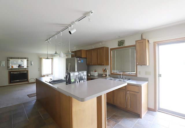 kitchen with a kitchen island, rail lighting, a sink, freestanding refrigerator, and light carpet