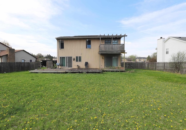 back of house featuring a fenced backyard, a lawn, a deck, and a balcony