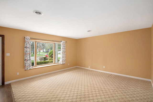 unfurnished room with baseboards, light colored carpet, and visible vents