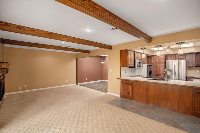 kitchen with carpet floors, baseboards, open floor plan, a sink, and appliances with stainless steel finishes