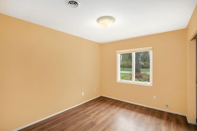 empty room with baseboards, wood finished floors, and visible vents