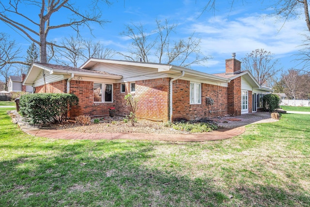 view of side of property featuring a lawn, a chimney, and brick siding