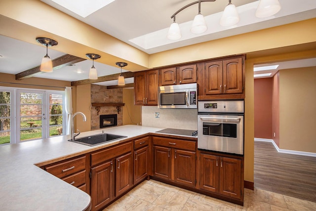 kitchen with a skylight, appliances with stainless steel finishes, tasteful backsplash, a sink, and a peninsula