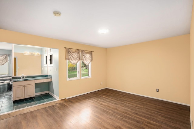 unfurnished room featuring a sink, baseboards, and dark wood-style flooring