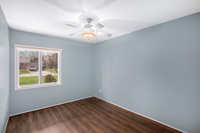 spare room with baseboards, dark wood finished floors, and ceiling fan