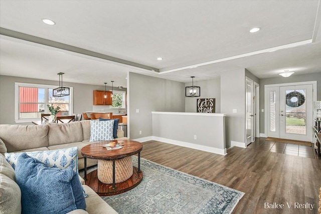 living room featuring baseboards, recessed lighting, wood finished floors, and a tray ceiling