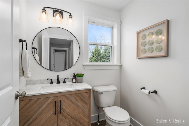 bathroom featuring toilet, baseboards, and vanity