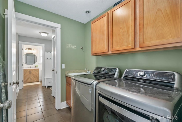 laundry area featuring cabinet space, a sink, tile patterned flooring, baseboards, and washer and clothes dryer