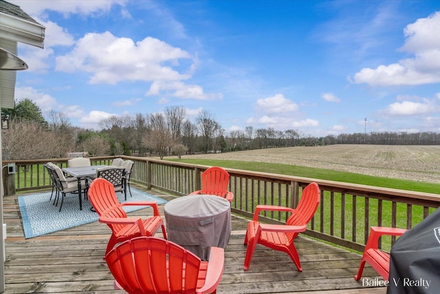wooden deck with a rural view and outdoor dining space