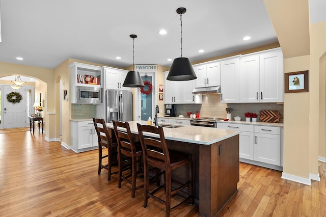 kitchen with decorative backsplash, light wood-type flooring, a sink, stainless steel appliances, and recessed lighting