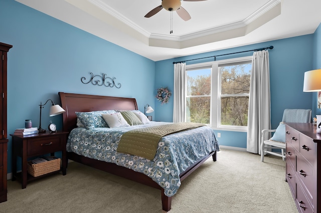 bedroom with ornamental molding, baseboards, ceiling fan, light colored carpet, and a tray ceiling