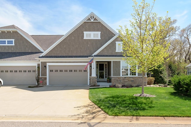 craftsman-style home featuring a garage, a front lawn, stone siding, roof with shingles, and driveway
