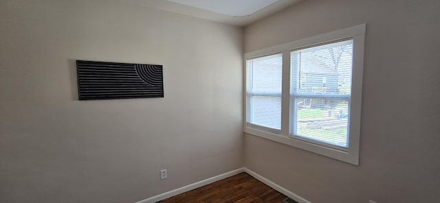 spare room with plenty of natural light, baseboards, and dark wood-style floors