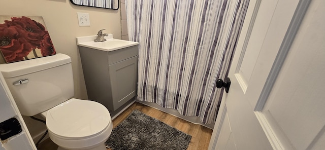 bathroom with toilet, a shower with curtain, wood finished floors, and vanity