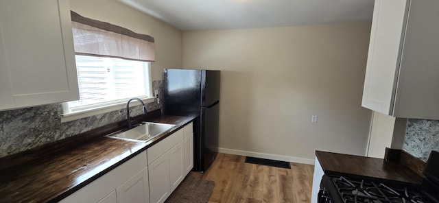 kitchen with backsplash, visible vents, a sink, black appliances, and butcher block counters